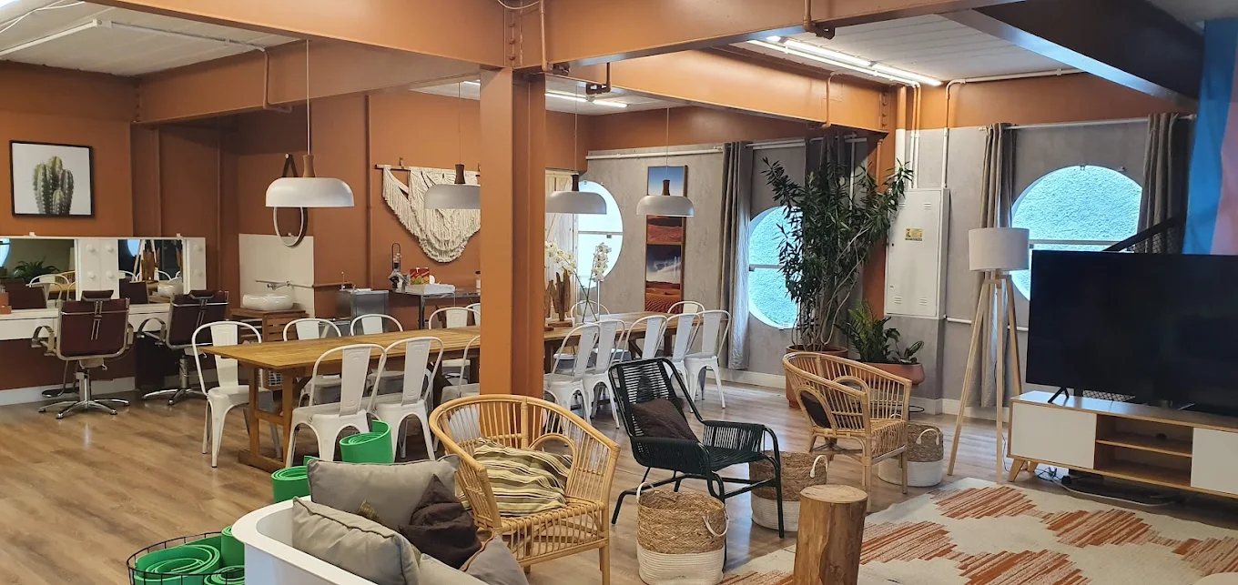 Sala de convivência da Casa Florescer, com paredes em terracota, móveis de madeira e palha, plantas e luz natural.