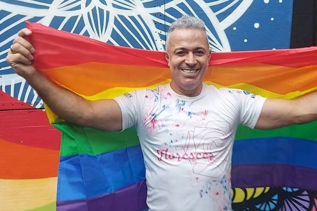Beto Silva segurando uma bandeira LGBT em evento público.